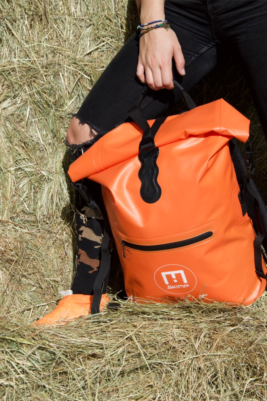 Orange SKIMP Adventurer backpack carried by hand