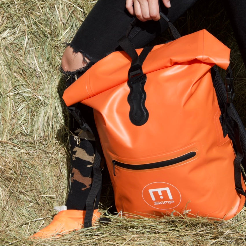 Orange SKIMP Adventurer backpack carried by hand