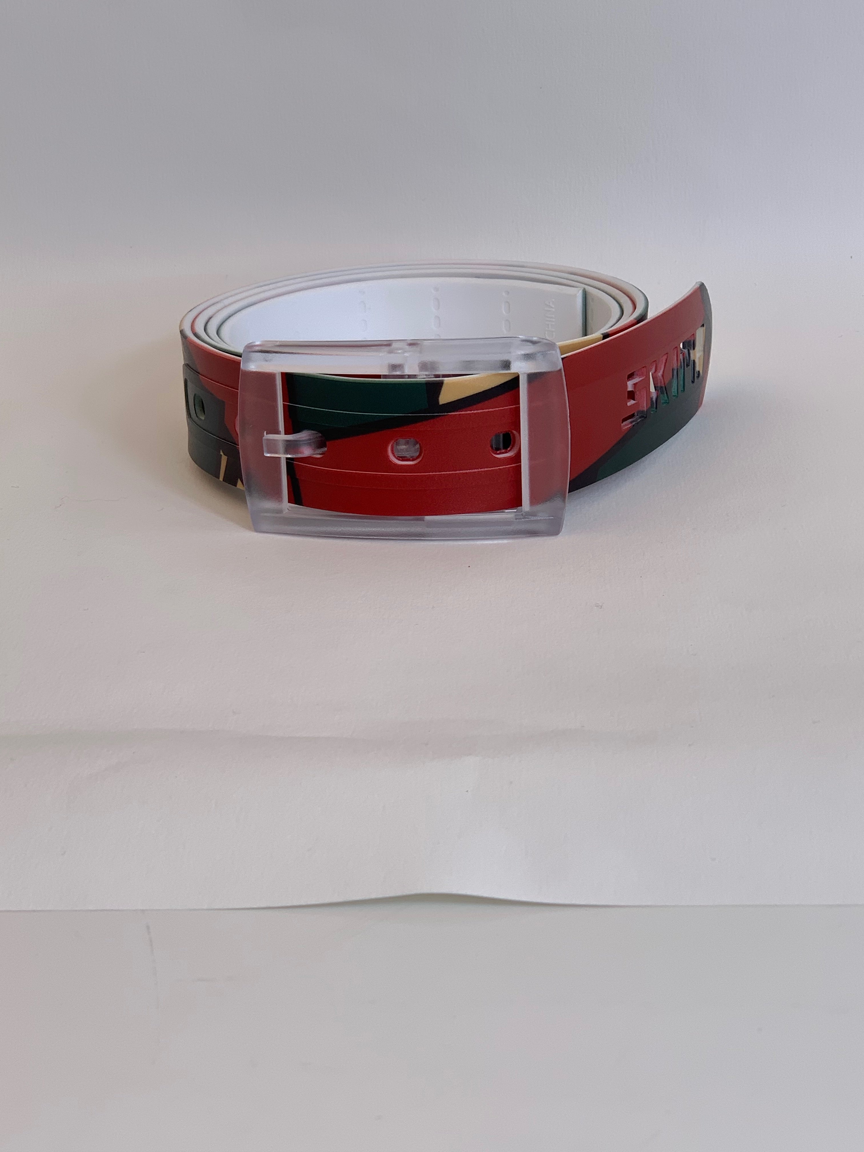 SKIMP Red Geo Belt – metal-free waterproof belt with red, dark green, cream and black geometric print and clear buckle
